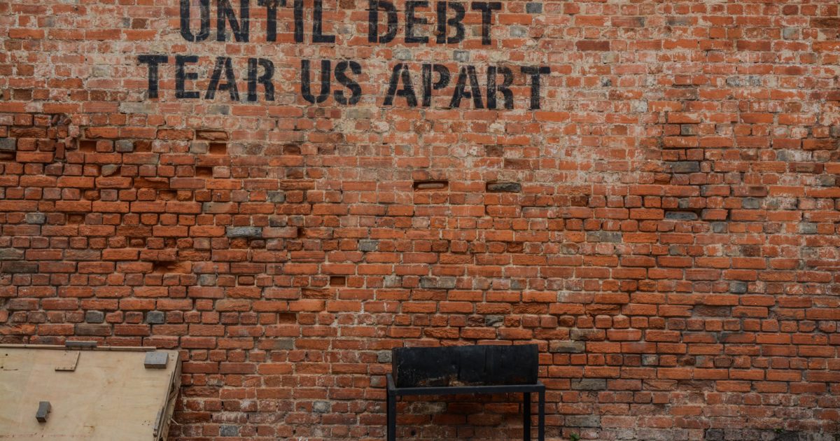 until debt tear us apart painted on brick wall